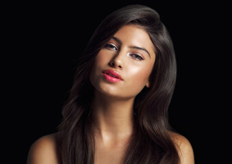 Obraz premium Portrait, hair care and woman with cosmetics, shine or cosmetics on black studio background. Face, person or model with glow, aesthetic or grooming routine with dermatology, beauty or salon treatment