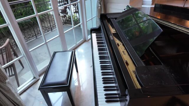 Video footage of Grand Piano with black and white piano keys, Camera moves from the side 45 degree smoothly.