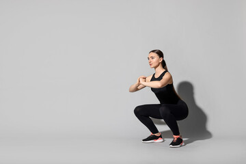 Obraz premium Young woman doing aerobic exercise on light grey background. Space for text