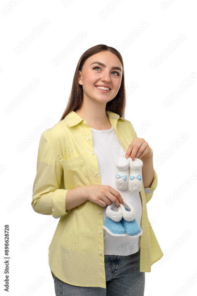 Wall mural Expecting twins. Pregnant woman holding two pairs of baby shoes on white background