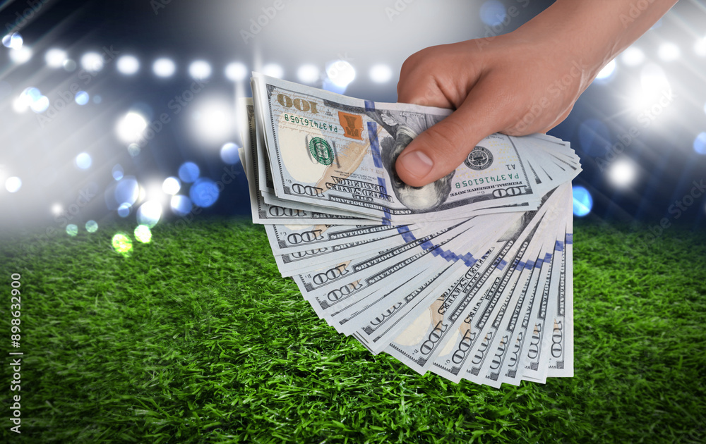 Wall mural man holding dollar bills at stadium, closeup