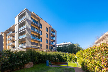 This image features a modern apartment complex with multiple balconies and a well-maintained green garden in the foreground, reflecting contemporary living and community design.
