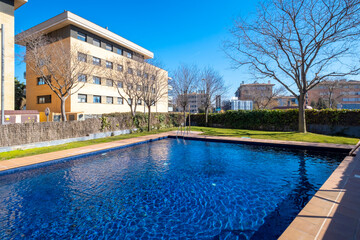 The image showcases a strikingly blue swimming pool with residential buildings in the background, capturing the essence of modern relaxation facilities in a peaceful neighborhood.