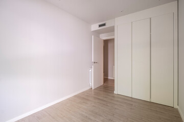 Interior of a spacious bedroom adorned with minimalistic decor, emphasizing abundant natural light and simple, clean lines for a calming atmosphere.