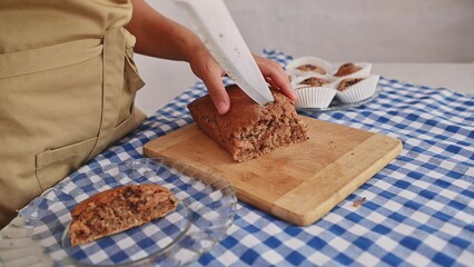 Homemade baking scene with person slicing fresh bread on wooden cutting board