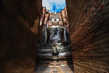 Big buddha image with ruined historical landmark in Sukhothai, Thailand