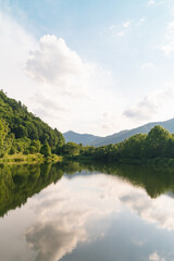 Beautiful view of the sky reflections on lake's water. Mountains and hills landscape.