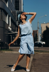 Fototapeta premium A cheerful girl in a blue suit walks along a sunny city street