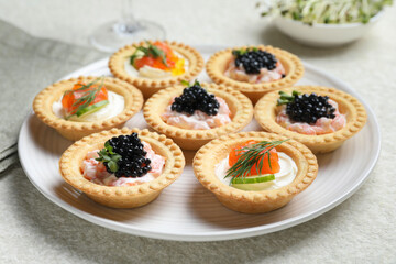 Delicious canapes with salmon and caviar on beige textured table, closeup