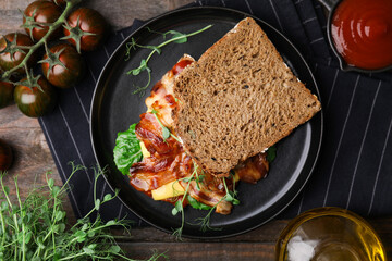 Tasty sandwich with bacon and microgreens served on wooden table, flat lay