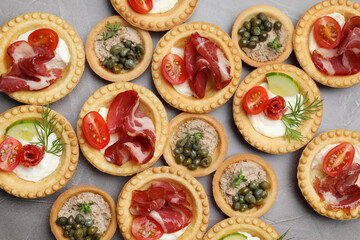 Different delicious canapes on grey textured table, flat lay