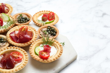 Different delicious canapes on white marble table, space for text