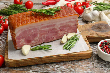 Piece of raw bacon with spices and cherry tomatoes on wooden table