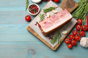 Piece of raw bacon with spices and tomatoes on light blue wooden table, flat lay. Space for text