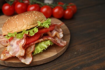 Delicious burger with bacon, tomato and lettuce on wooden table, space for text