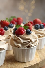 Tasty cupcakes with different berries and mint on wooden table, closeup