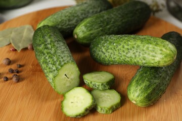 Board with fresh cucumbers and spices on table, closeup