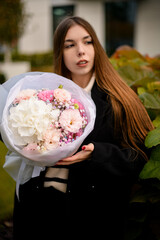 Fototapeta premium Pretty young woman neatly holding a delicate bouquet of various pink and white flowers