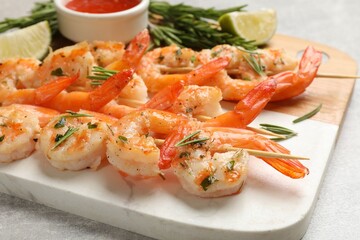 Skewers with delicious grilled shrimps served on grey table, closeup