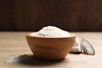 Fresh coconut flour in bowl and nut on wooden table
