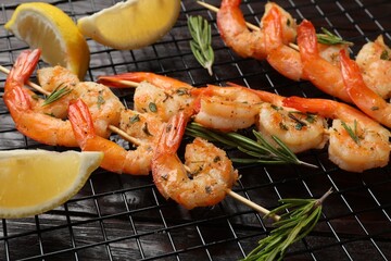 Skewers with delicious grilled shrimps, herbs and lemon on wooden table, closeup