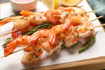 Skewers with delicious grilled shrimps on table, closeup