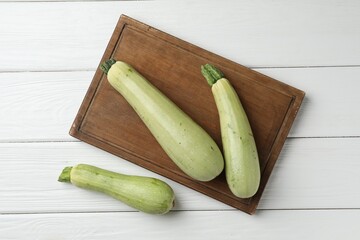 Raw green zucchinis on white wooden table, top view