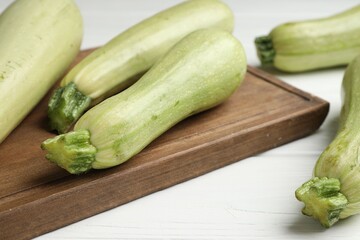 Raw green zucchinis on white wooden table, closeup
