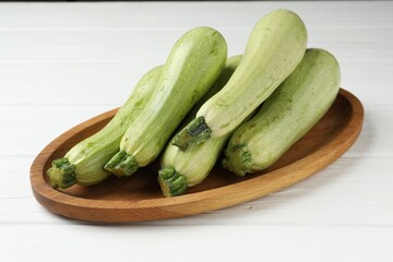 Raw green zucchinis on white wooden table