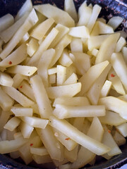 Freshly cut raw potato fries ready for frying in a pan
