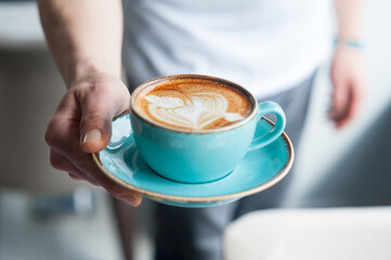 Male barista holds a beautifully created latte art heart with arrow design