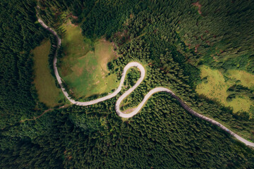 Aerial view of the road passing through the mountain and green forest. Curve asphalt road on mountain.