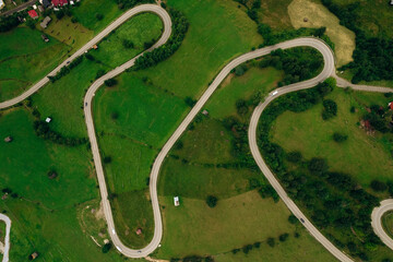 Aerial view of the road passing through the mountain and green forest. Curve asphalt road on mountain.