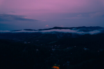 Mountains with pine forest in the fog at sunset. Foggy landscape with fir forest.