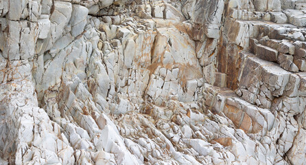 Close-up of textured rocky surface with various shades of grey and brown, displaying intricate...