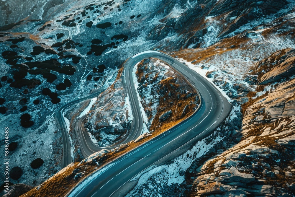 Poster Aerial view of a winding mountain road with snow-capped peaks and lush green valleys