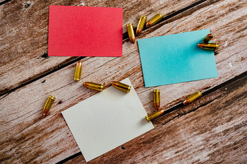 red blue and white empty notes with scattered 9 mm bullet ammunition on wood plank background