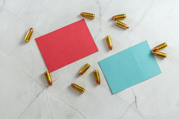 red empty note and blue empty note with scattered bullets on white marble stone background
