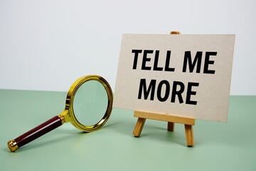 Tell me more text on paper card with magnifying glass on green background