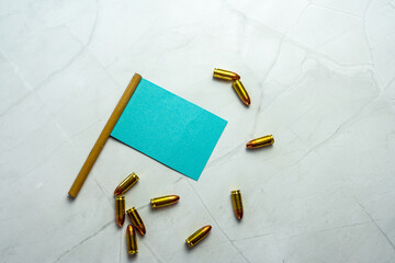 blue empty miniature flag with empty copyspace and scattered bullets on white marble background