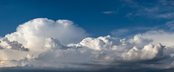 Fototapeta premium Sky panorama with cumulonimbus clouds. Natural landscape with fluffy clouds, water condensation in the atmosphere. Natural background for banner