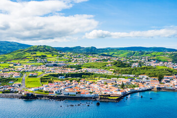 View of Horta town on ocean coast with green farming hills in background, Faial island, Azores, Portugal