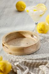 Yellow lemons and drink in cocktail glass on wooden table. Close up and wooden tray with copy space for food and drinks and products.