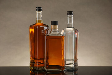 Bottles of different alcoholic drinks on table against gray background