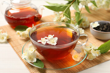 Hot jasmine tea in cup and flowers on white wooden table