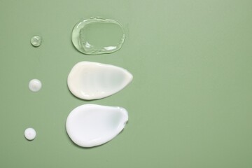 Face cream and gel on green background, top view. Space for text