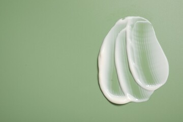 Face cream on green background, top view. Space for text