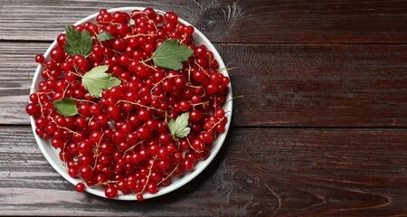 Fresh red currants and leaves on wooden table, top view. Space for text