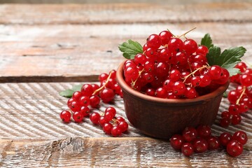 Fresh red currants in bowl on wooden table, closeup. Space for text