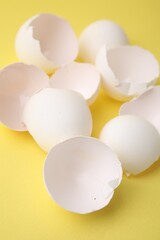 Pile of broken eggshells on yellow background, closeup